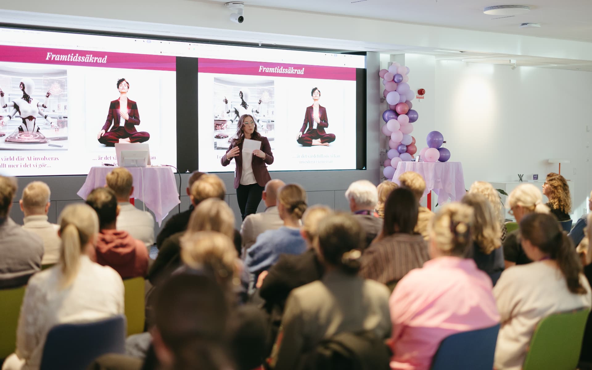 Annie Cedersjö föreläser på scen inför en publik som sitter vänd mot henne.